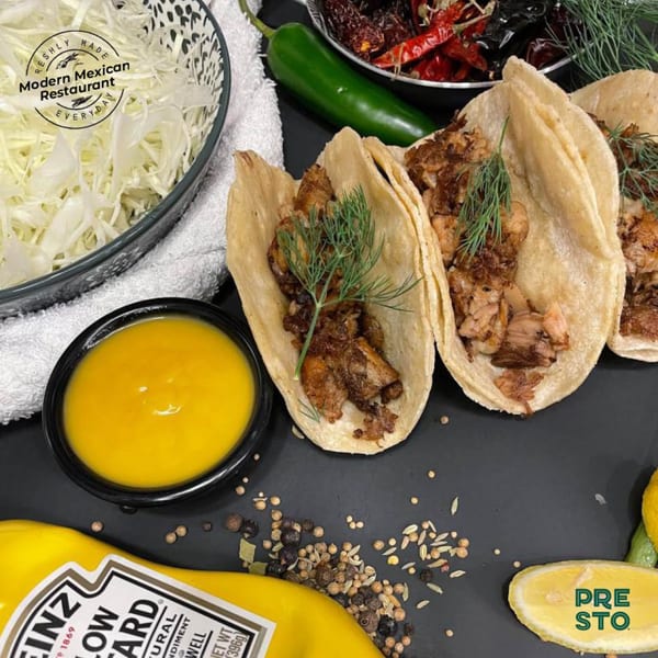 Three Presto Fresh Cafe tacos with meat and dill, alongside shredded cabbage, sauce, and spices.