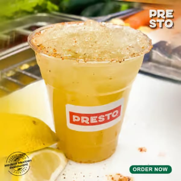 A Presto Fresh Cafe Mexican drink in a clear cup with a spiced rim and lemon slices.