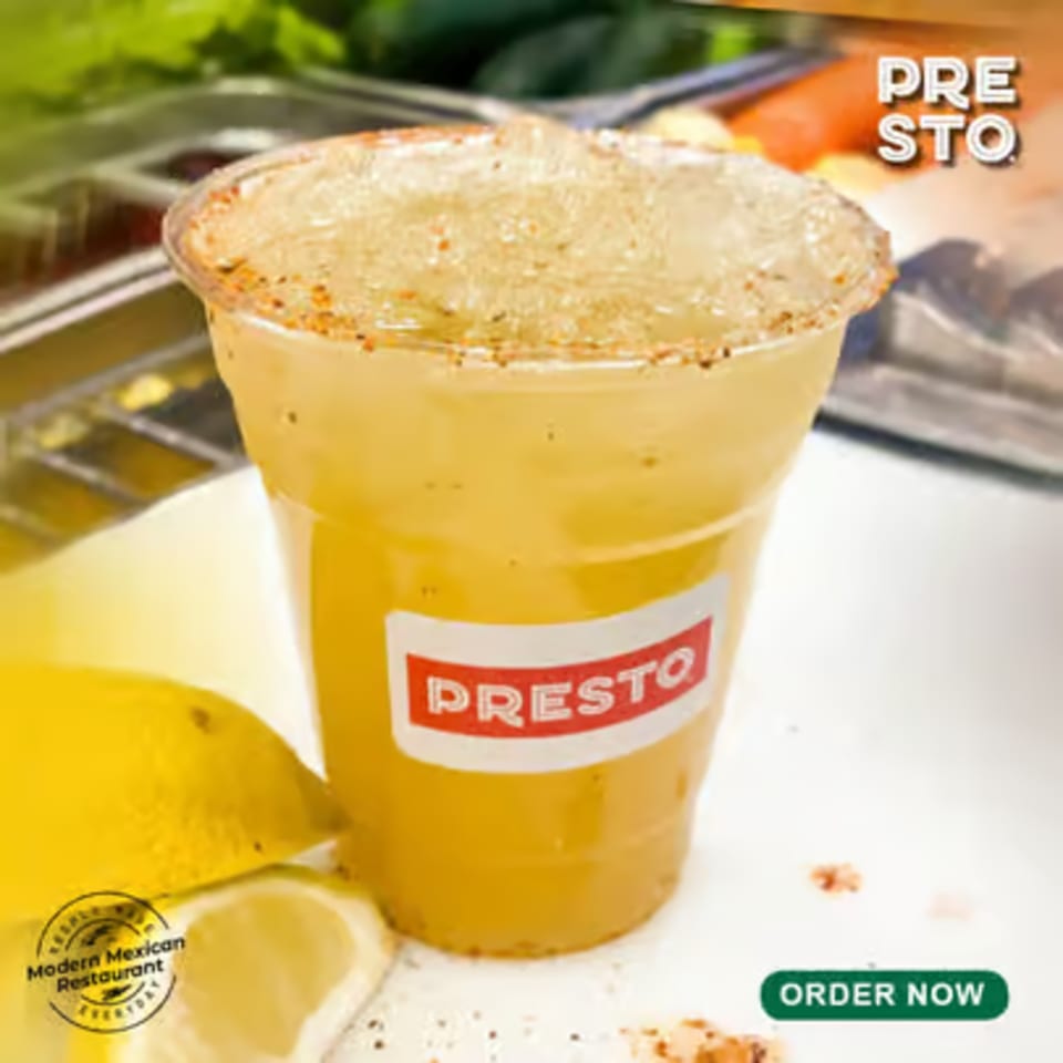 A Presto Fresh Cafe Mexican drink in a clear cup with a spiced rim and lemon slices.