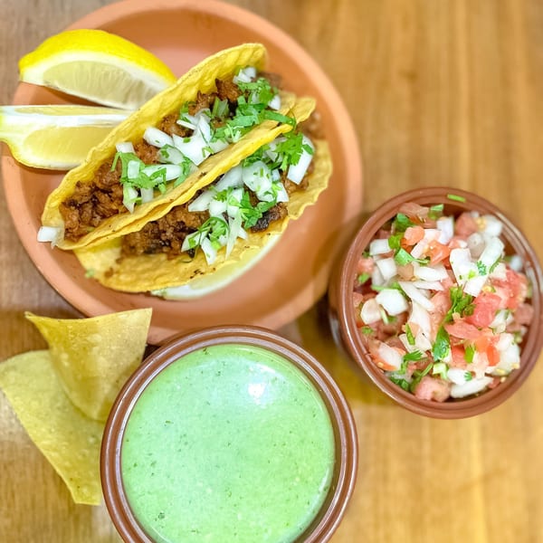 Two PRESTO FRESH CAFE CORP tacos with lemon, salsa, green sauce, and tortilla chips.